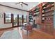 Office with built-in shelving, hardwood floors, exterior views through French doors and transom window, and a ceiling fan at 104 N Royal Ascot Dr, Las Vegas, NV 89144