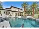 Exterior view of a home with a pool, tropical landscaping, and a covered veranda at 104 N Royal Ascot Dr, Las Vegas, NV 89144