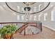 Curved staircase with a wrought iron railing, windows and a chandelier, highlighting the home's architectural design at 104 N Royal Ascot Dr, Las Vegas, NV 89144