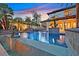 A large, in-ground swimming pool with lush landscaping and rock waterfalls is featured at twilight at 104 N Royal Ascot Dr, Las Vegas, NV 89144