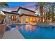 The in-ground swimming pool features waterfalls, lush landscaping, and multiple seating areas at dusk at 104 N Royal Ascot Dr, Las Vegas, NV 89144