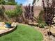 Lush backyard with artificial turf, decorative rock, and a quaint brick-lined garden bed at 11005 Edina Ct, Las Vegas, NV 89144