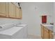 Functional laundry room with ample storage cabinets, washer, dryer, and a convenient utility sink at 2167 Fairweather St, Henderson, NV 89052