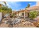Backyard oasis featuring a pergola with lounge chairs, rock features, and tropical trees at 2766 Chokecherry Ave, Henderson, NV 89074