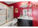 Bathroom featuring a white vanity, red walls, and white tile shower with gold trim at 2766 Chokecherry Ave, Henderson, NV 89074