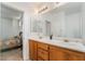 Bathroom featuring double sinks with wood cabinets, large mirror, and an open doorway to the bedroom at 2851 Glistening Grove Ave, Henderson, NV 89052