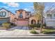 Two-story home with a pink garage door, archway and a small balcony on a sunny day at 2851 Glistening Grove Ave, Henderson, NV 89052