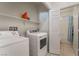 Organized laundry room featuring modern washer and dryer units, shelves, and access to a bright bathroom at 2851 Glistening Grove Ave, Henderson, NV 89052