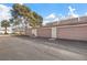 Three-car garage exterior with brown doors and an adjacent parking area with mature landscaping at 3365 Zephyr Ct, Las Vegas, NV 89121
