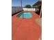 Private backyard swimming pool with a unique red concrete deck and a chain-link fence at 3424 Mount Charleston Dr, Pahrump, NV 89048