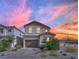 Two-story home with a two-car garage, desert landscaping, a brick-paved driveway, and stunning sunset view at 393 Desert Cadence St, Henderson, NV 89011