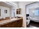 Bathroom with granite counter, wood cabinets, large mirror, and adjacent bedroom view at 4129 Fabulous Finches Ave, North Las Vegas, NV 89084