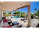 A covered patio with outdoor furniture next to the pool and a manicured backyard at 4129 Fabulous Finches Ave, North Las Vegas, NV 89084