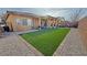 Extensive backyard features synthetic grass, a patio with seating, and lush desert landscaping at 4780 Lorenzo Way, Pahrump, NV 89061