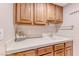 Functional laundry room with tiled countertops, a sink, and wooden cabinetry at 5501 Painted Sunrise Dr, Las Vegas, NV 89149