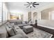 Spacious living room featuring a comfortable grey sectional couch, ceiling fan and dark wood floors at 5578 Holcomb Bridge Ct, Las Vegas, NV 89149