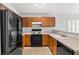 A view of the kitchen featuring oak cabinets, black appliances, and tiled flooring at 6037 Soft Springs Ave, Las Vegas, NV 89130