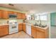 Efficient kitchen with white appliances, wooden cabinets, and tiled flooring at 6066 El Sol Dr, Las Vegas, NV 89142