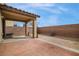 This backyard has a covered patio with tile pavers and a dirt area surrounded by a brick wall with a bright blue sky above at 8646 Mesquite Hills St, Las Vegas, NV 89139