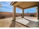 This backyard has a covered patio with tile pavers and a dirt area surrounded by a brick wall with a bright blue sky above at 8646 Mesquite Hills St, Las Vegas, NV 89139