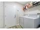 This home's laundry room has a side by side washer and dryer with storage shelf above and a door leading to another room at 8646 Mesquite Hills St, Las Vegas, NV 89139