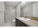 This bathroom includes granite countertops, dark cabinets, and a glass shower with beige tiles at 88 Pristine Glen St, Las Vegas, NV 89135