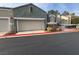 View of a two-car garage and the front of a home with stone accents and mature landscaping at 9126 Haddington Ln, Las Vegas, NV 89145