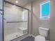 Modern bathroom featuring a glass-enclosed shower, toilet, and a bright window at 10768 Ditchburn Ct, Las Vegas, NV 89166