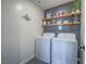 Bright laundry room boasts a modern washer and dryer, with stylish shelves for storage and decor at 10768 Ditchburn Ct, Las Vegas, NV 89166