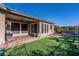 The covered patio and backyard feature brick, artificial turf, mature landscaping, seating, and an outdoor grill at 2931 Raywood Ash Dr, Las Vegas, NV 89138