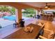 Inviting covered patio with an outdoor dining set overlooking the pool, tiki bar, and beautifully landscaped backyard at 3132 El Camino Rd, Las Vegas, NV 89146