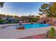 Resort-style backyard featuring a pool with rock waterfall, slide, and a charming tiki hut dining area at 3132 El Camino Rd, Las Vegas, NV 89146