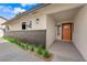 Front exterior showcasing the home's light stucco and brick details, trimmed landscaping, and a vibrant orange front door at 3228 Robin Cir, Las Vegas, NV 89121