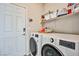 Functional laundry room with modern washer and dryer, storage shelves, and convenient access door at 4423 Creekside Cavern Ave, North Las Vegas, NV 89084