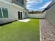 Backyard with artificial grass, stone landscaping, white fence and sliding door to the house at 545 Thea St # 1315, Henderson, NV 89052