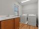 The Laundry Room features wood cabinets, a utility sink, and white washer and dryer set at 5808 Sierra Cliff St, North Las Vegas, NV 89031