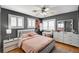 Bedroom with dark gray walls, wood floor, windows with white shutters, and a ceiling fan at 6538 Astorville Ct, Las Vegas, NV 89110