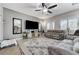 Comfortable living room featuring tiled flooring, large windows, ceiling fan and a modern entertainment center at 6971 Moaning Cavern St, Las Vegas, NV 89131