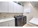 Well-equipped laundry room with front load washer/dryer, sink, and ample storage cabinets at 7264 Summer Duck Way, North Las Vegas, NV 89084