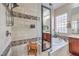 Close up of glass-enclosed shower with upgraded fixtures and travertine tile at 7264 Summer Duck Way, North Las Vegas, NV 89084