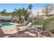 Landscaped backyard with a kidney-shaped pool, lounge chairs, patio furniture, and mature trees and bushes at 841 Rusty Anchor Way, Henderson, NV 89002