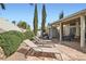 Stone backyard patio with lounge chairs, covered sitting area with dining table, and well-maintained landscaping at 841 Rusty Anchor Way, Henderson, NV 89002