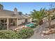 A cozy backyard view featuring a pool, lush greenery, and a covered patio with outdoor seating at 841 Rusty Anchor Way, Henderson, NV 89002