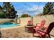 Cozy backyard seating area with a brick fire pit, surrounded by lush landscaping and a refreshing pool at 947 Rainbow Rock St, Las Vegas, NV 89123