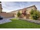 View of backyard featuring artificial grass and a stone-tiled patio with a decorative retaining wall at 10376 Sadie Blake Ave, Las Vegas, NV 89166