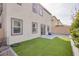 View of the backyard featuring artificial grass and a stone-tiled patio, perfect for outdoor entertaining at 10376 Sadie Blake Ave, Las Vegas, NV 89166