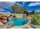 An outdoor view of a backyard pool with a rock waterfall feature and a covered gazebo in the background at 11072 Pentland Downs St, Las Vegas, NV 89141
