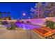 Backyard with a sparkling pool, rock waterfall feature and lounge chairs at twilight at 11072 Pentland Downs St, Las Vegas, NV 89141