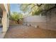 Wide gravel backyard featuring a brick wall, potted plants, and shade trees at 11204 Newbury Hills Ave, Las Vegas, NV 89138
