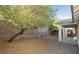 Backyard with gravel, privacy wall, covered patio and mature tree at 11204 Newbury Hills Ave, Las Vegas, NV 89138